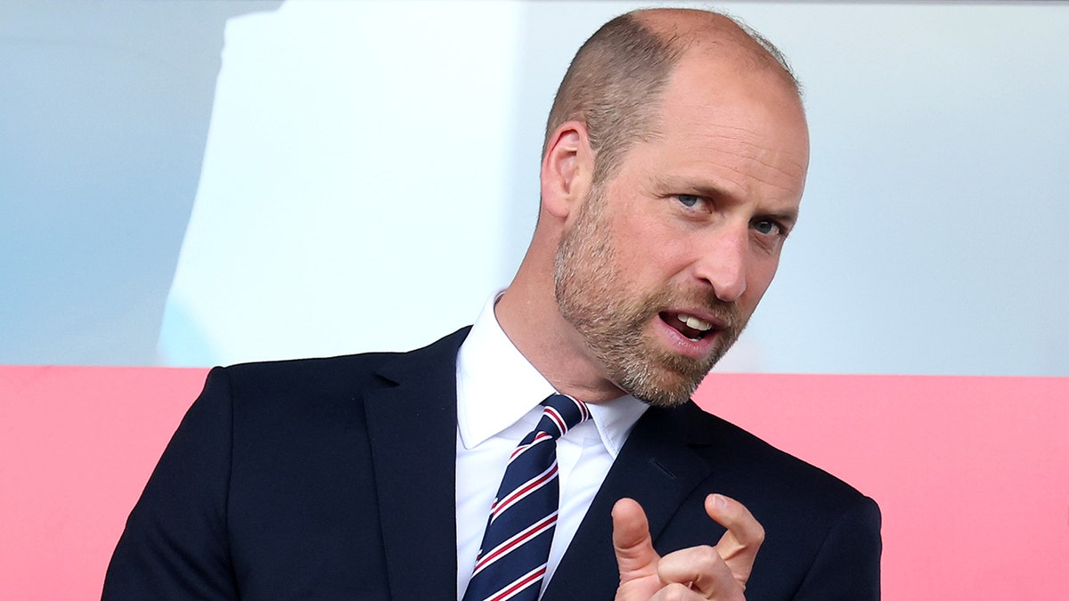 Prins William midden in een gesprek met een zwarte blazer en een gestreepte stropdas.
