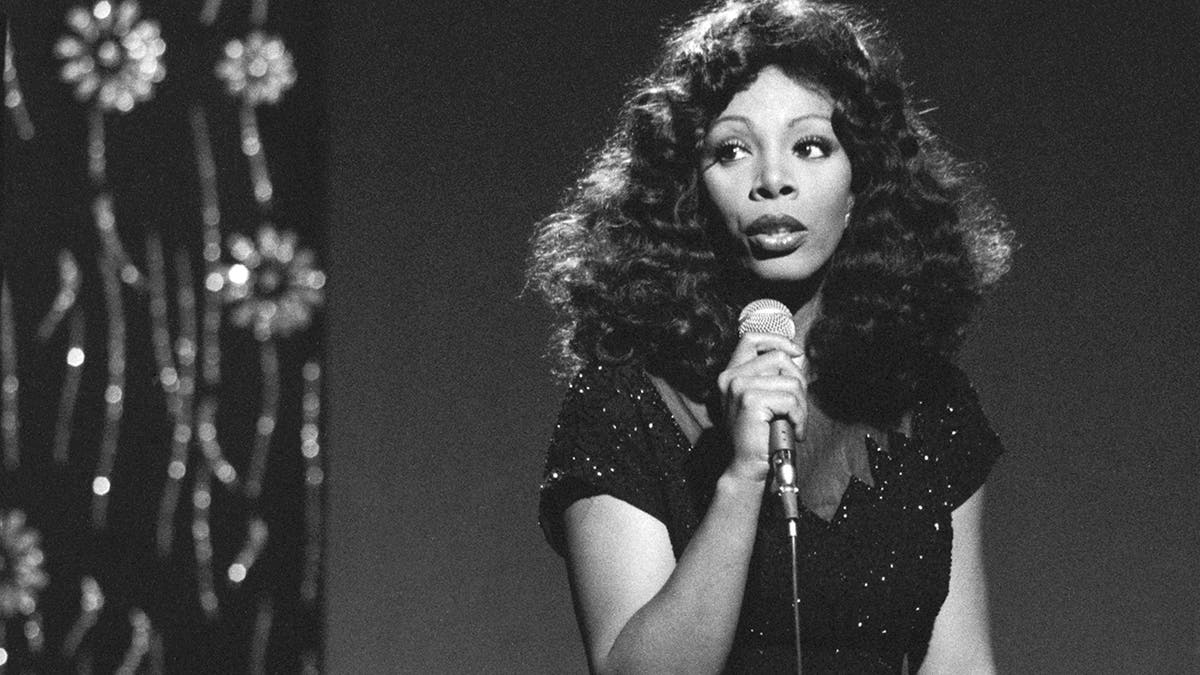 Een zwart-wit foto van Donna Summer met een microfoon in haar handen