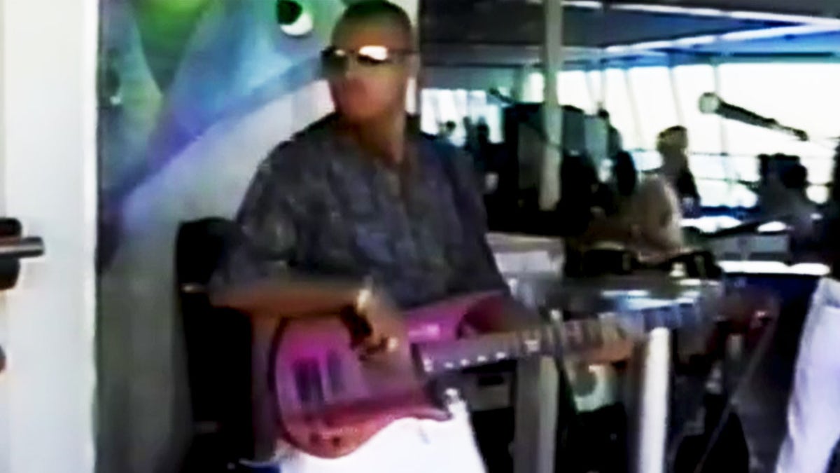 Alastair Douglas draagt een donker shirt en speelt op een paarse gitaar.