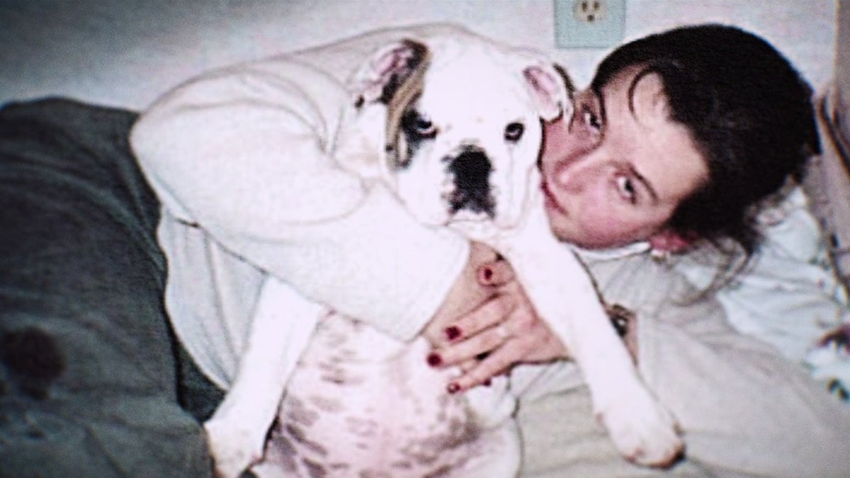 Amy Bradley draagt een witte trui en houdt haar buldog vast.