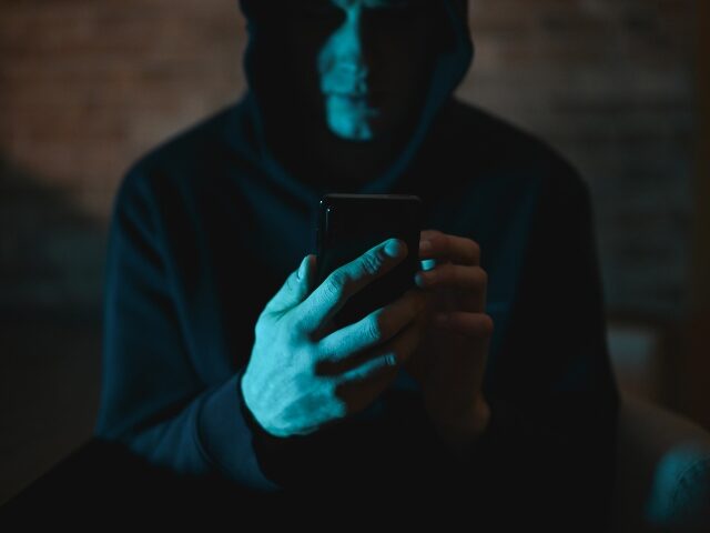 engerd die in het donker naar zijn telefoon kijkt