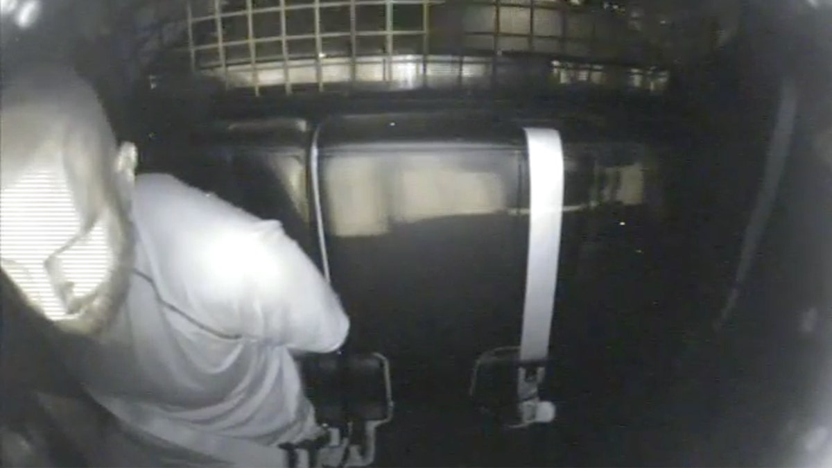 Jeremy Guthrie geboeid achterin politieauto