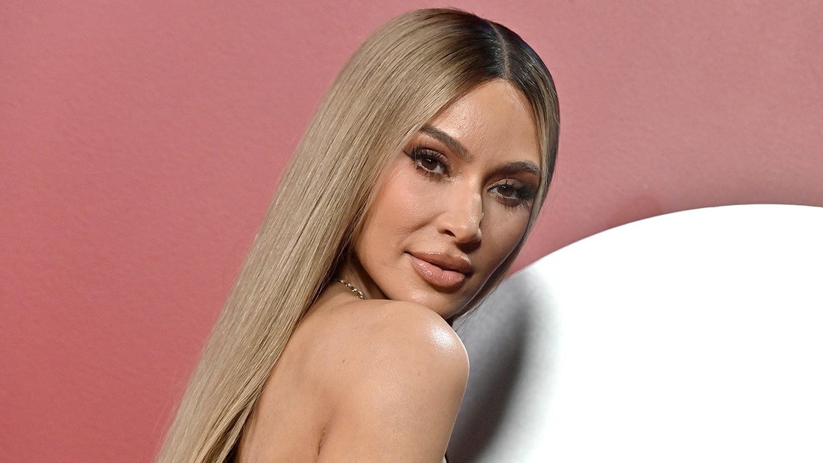 Kim Kardashian met blond haar kijkt over haar schouder op het GQ Men of the Year evenement