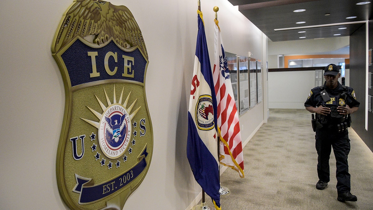 Wetshandhaver bij ICE-badge op muur