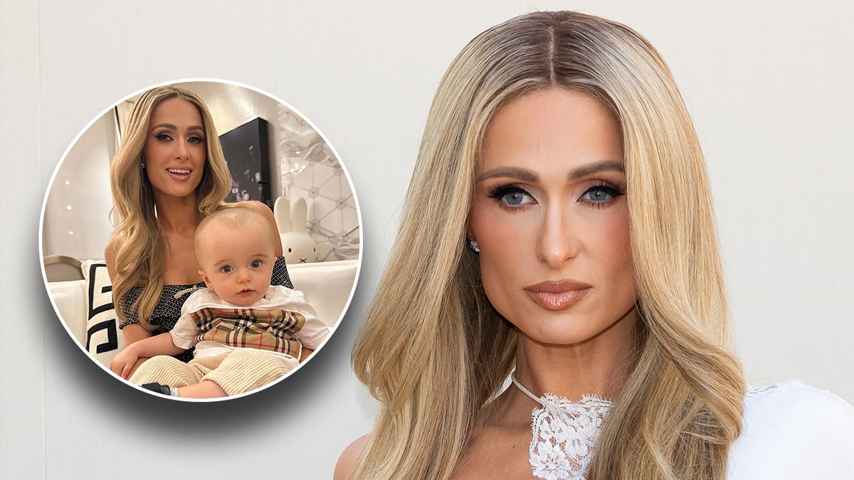 Paris Hilton in een wit topje kijkt serieus op het tapijt met een foto van haar terwijl ze zoon Phoenix op haar schoot houdt
