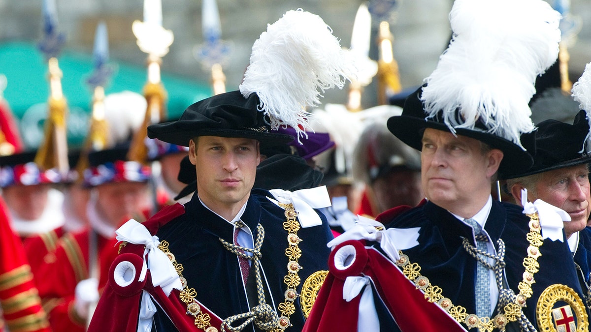Prins William en Prins Andrew zien er ernstig uit in koninklijke gewaden terwijl ze naar buiten marcheren.
